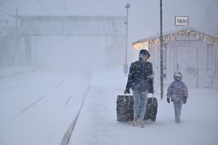 Menschen gehen bei starkem Schneefall am Bahnhof in der Stadt Åre in Schweden, nachdem der Zugverkehr eingestellt wurde. 