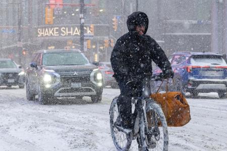 Ein Mann fährt an einem verschneiten Tag in Toronto auf einem E-Bike.