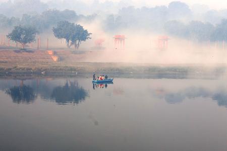 Ein Boot fährt bei Nebel auf dem Yamuna-Fluss.