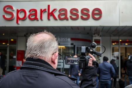 Ein Medienvertreter steht mit einer Kamera vor der Sparkassenfiliale in Buer.