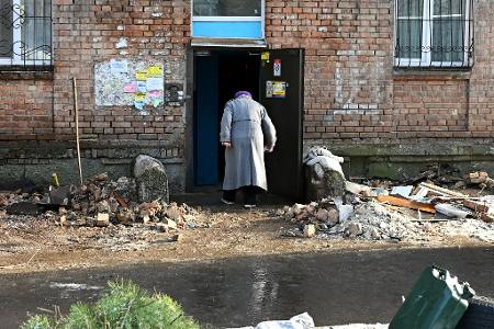Eine Frau geht in ein beschädigtes Haus.