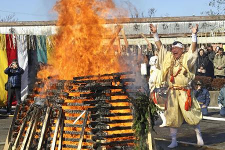Ein Mönch wirft Glücksbringer und Amulette als Dank in ein Feuer.