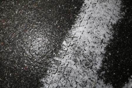 Frische Reifenspuren eines Winterreifens auf spiegelglatter Straße zeigen die winterlichen Straßenverhältnisse im Harz.