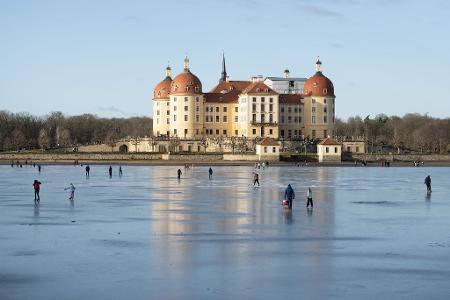Schlittschuhläufer sind auf dem Eis vor Schloss Moritzburg in Sachsen unterwegs.