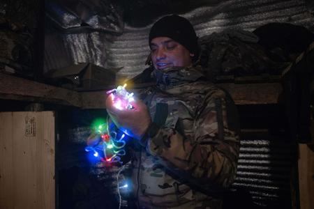 Dieses vom Pressedienst der 93. mechanisierten Brigade der Ukraine zur Verfügung gestellte Foto zeigt einen Soldaten an der Frontlinie in der Nähe von Kostjantyniwka in der Region Donezk, der eine Neujahrsgirlande hält.