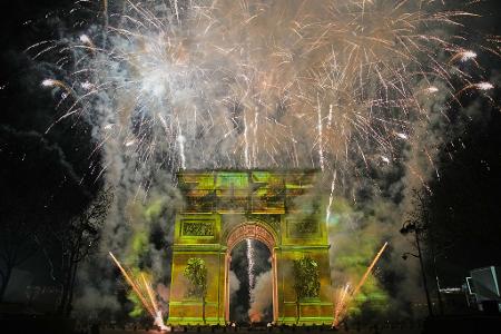 Eine Lichtshow wird auf den Arc de Triomphe projiziert, während ein Feuerwerk im Rahmen der Neujahrsfeierlichkeiten auf den Champs Elysees gezündet wird.
