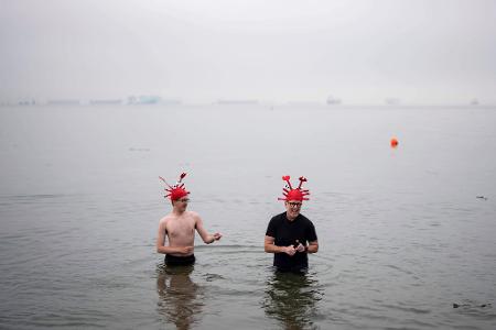 Menschen waten im Wasser während des olar Bear Swim in Vancouver.