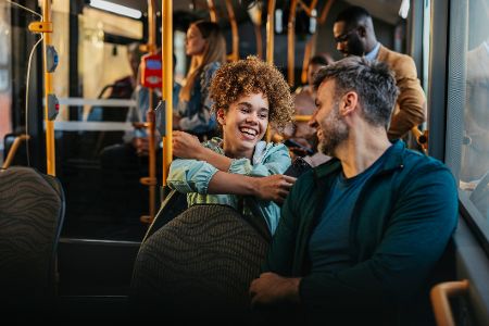 Junge Frau und junger Mann lachen zusammen in einem Bus