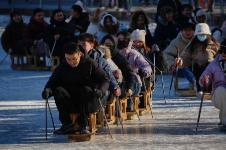 Wochenendspaß auf dem Eis: Stuhl-Skifahren im Park von Peking