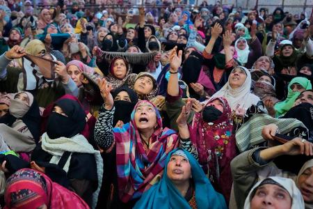 Muslimische Gläubige aus Kaschmir beten, während ein Oberpriester eine Reliquie zeigt.