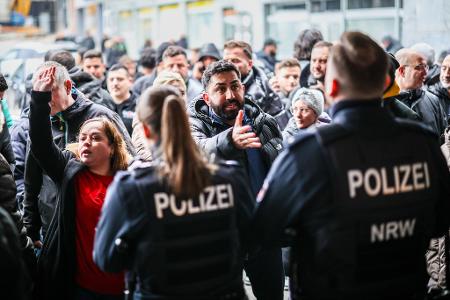 Aufgebrachte Kunden diskutieren vor der Sparkassenfiliale mit Polizeibeamten (Archivfoto)