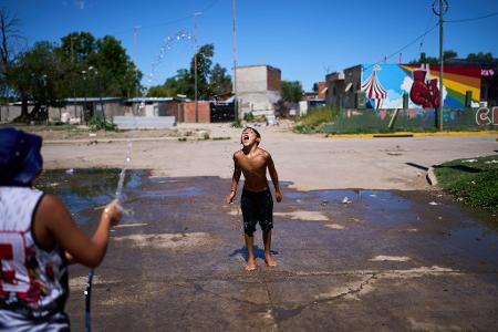 Alejo Quiroga fängt Wasser aus einem Schlauch, um sich wegen der hohen Temperaturen am Stadtrand von Buenos Aires abzukühlen.