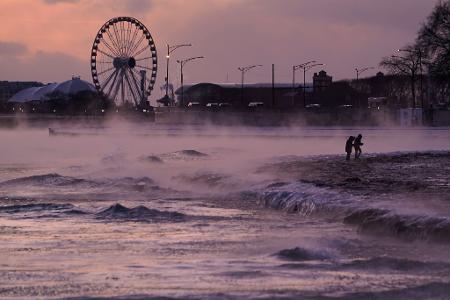 Menschen spazieren in Chicago über einen mit Eis bedeckten Strand am Ufer des Michigansees.