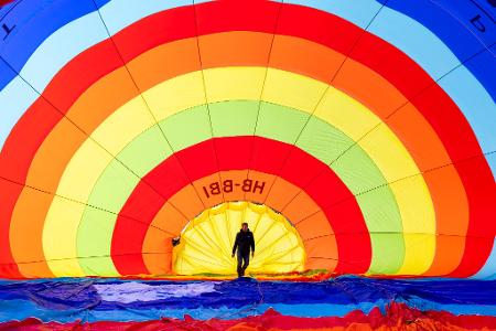 Ein Teammitglied überprüft seinen Heißluftballon vor dem Start während des 46. Internationalen Heißluftballon-Festivals in Chateau-d'Oex.